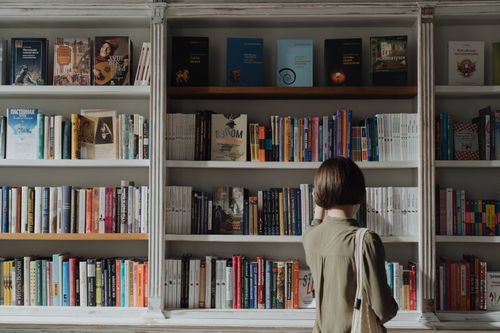 Free A woman browsing a large book collection in a cozy bookstore, exploring literature. Stock Photo