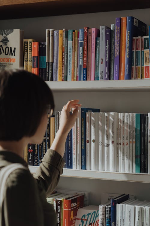 Person in Black and White Long Sleeve Shirt Holding White Book