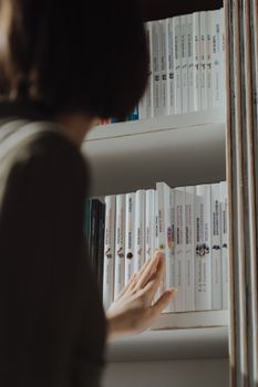 一个人检查书架上的书籍，捕捉到了好奇与学习的瞬间