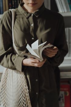 在宁静的图书馆里，一位穿着绿色休闲衬衫的女人正在浏览一本书