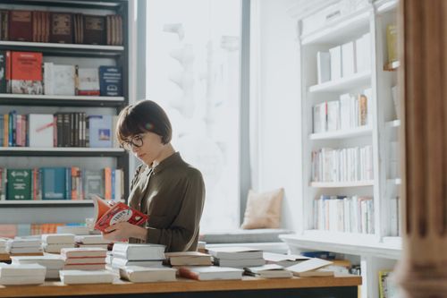 Free A woman enjoys reading in a bright and cozy bookstore setting. Stock Photo