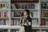 一位女士在舒适的书店里，手捧一本书，享受着宁静的氛围和丰富的文学选择