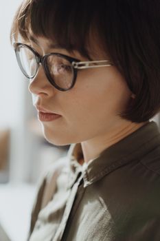 一位戴着眼镜的年轻女子在室内读书，神情专注，捕捉到了沉思的瞬间