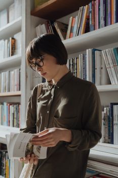 一位年轻女子戴着眼镜，在舒适的图书馆里看书