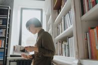 一名戴眼镜的女子在现代图书馆里看书，兼顾学习与休闲