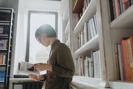 一名戴眼镜的女子在现代图书馆里看书，兼顾学习与休闲