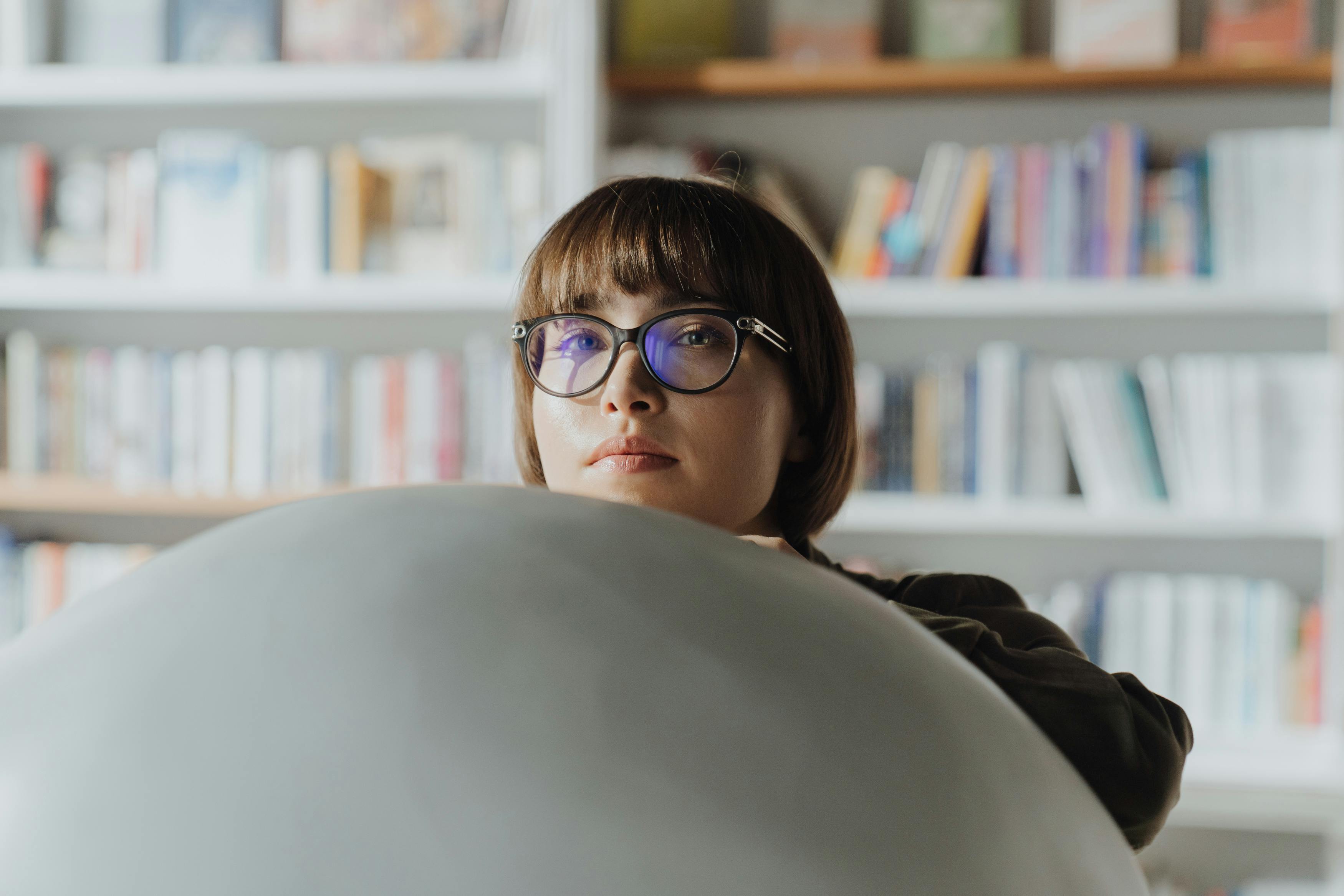 一名戴眼镜的女子在书店的书架旁沉思