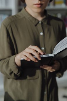 一名年轻女子穿着绿衬衫，在室内专心读书，体现了对学习的好奇心