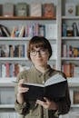 Woman in Green Button Up Shirt Wearing Black Framed Eyeglasses Reading Book