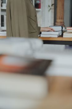 在图书馆里，一位妇女正专注地浏览桌上关于文学和学习的书籍