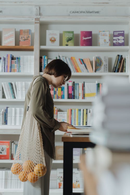 Mulher De Vestido Cinza De Manga Comprida Em Frente à Estante De Livros