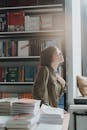 书店里，一名妇女若有所思地站着，阳光明媚的房间摆满了书籍