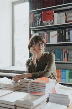 书店里，戴眼镜的女人在一堆书中沉思