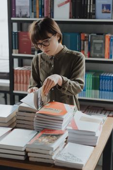 一位女士在一家舒适温馨的书店里浏览书籍，四周堆满了文学作品