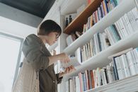 一位年轻女子在现代图书馆的书架间浏览，沉浸在文学世界里