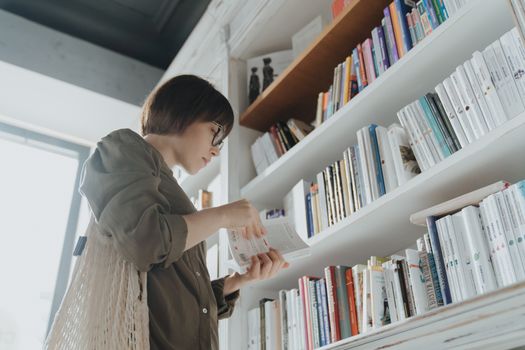 一位年轻女子在现代图书馆的书架间浏览，沉浸在文学世界里