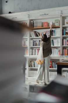 在现代书店里，一位女士拿起一本书，体现了休闲与学习的结合