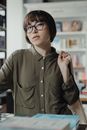 图书馆里，一位戴着眼镜的年轻女子被书籍环绕，表情若有所思