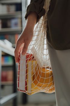 特写镜头中，一名妇女手持装满杂货和书籍的包袋，宣传零浪费生活方式