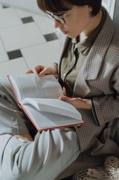 一位戴眼镜的女士在室内读书的特写镜头，展现了休闲与学习的氛围