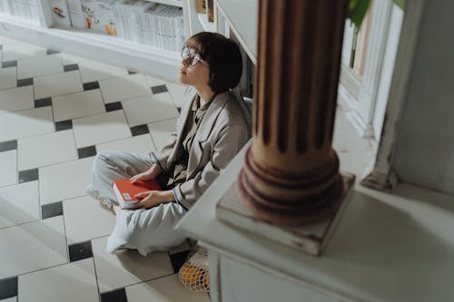 Free Wanita Dengan Kemeja Lengan Panjang Abu Abu Dan Hitam Duduk Di Ubin Lantai Keramik Putih Stock Photo