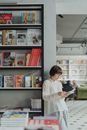 一位年轻女子在书店的书架旁读书