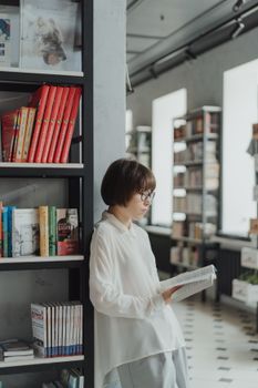 在现代图书馆或书店环境中，年轻女子正在读书