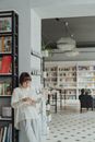 一位年轻女子正在一家时尚的书店里阅读，四周摆满了书籍和现代装饰