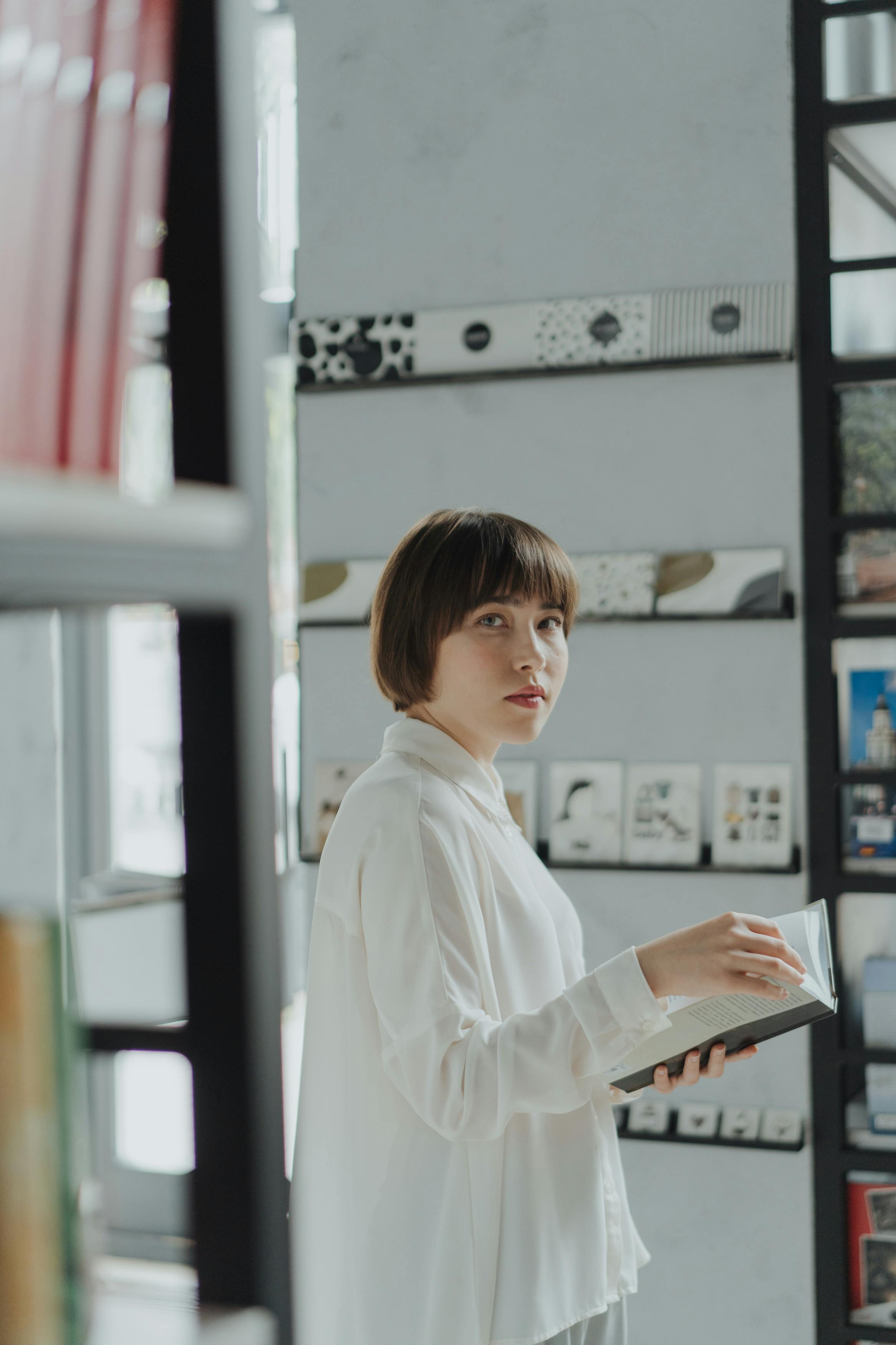 一名年轻女子穿着白衬衫，在时尚的室内图书馆里看书
