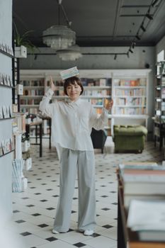 在舒适的书店环境中，年轻女子享受着头顶书籍平衡的乐趣