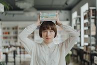 一位年轻女子在图书馆里用头顶着书取乐