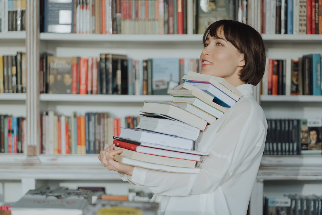 Free Woman in White Long Sleeve Shirt Reading Books Stock Photo
