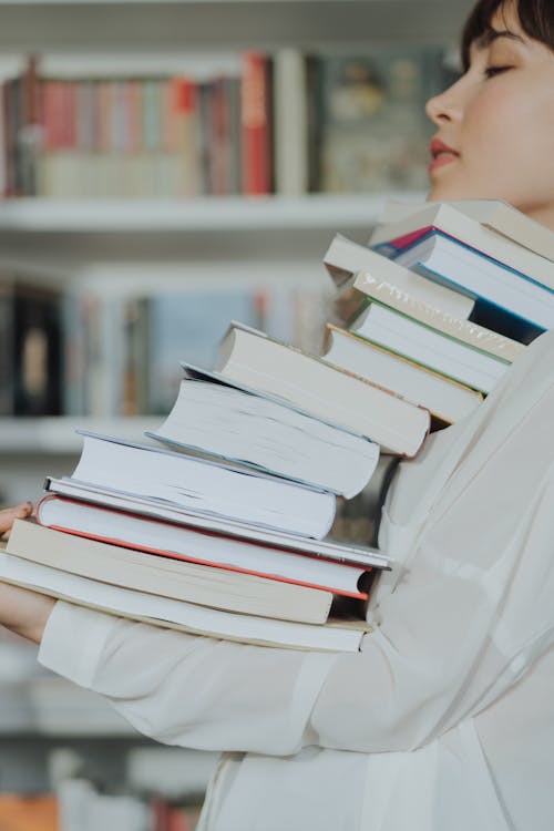 Free Woman Carrying a Stack of Books Stock Photo