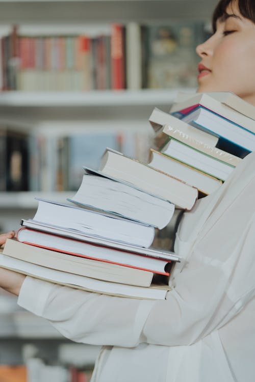 Person Reading Book on Book Shelf