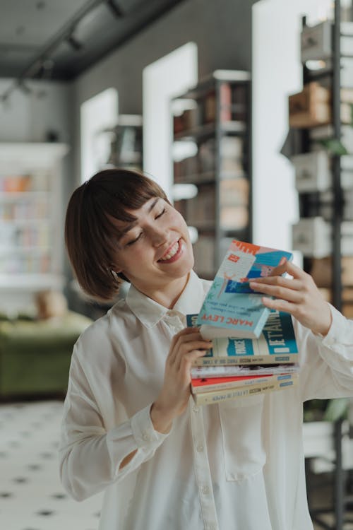 Woman in White Dress Shirt Holding Blue Book