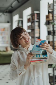 在现代图书馆里，一位穿着白衬衫的年轻女子拿着书微笑