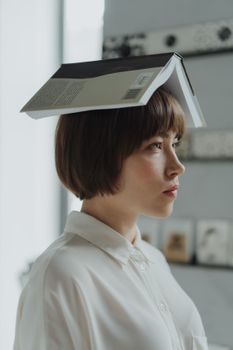 室内，一名妇女的肖像中，她头上平衡着一本书