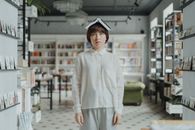 在现代图书馆里，一位穿着白衬衫的年轻女子正用头顶着一本书