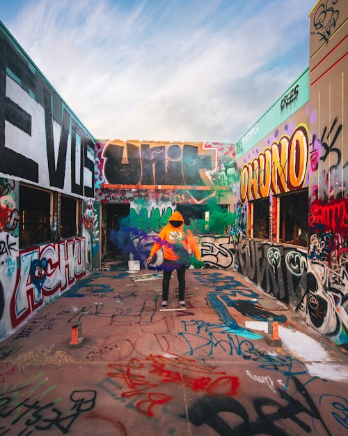 Man in Green Jacket Riding Bicycle Near Graffiti Wall