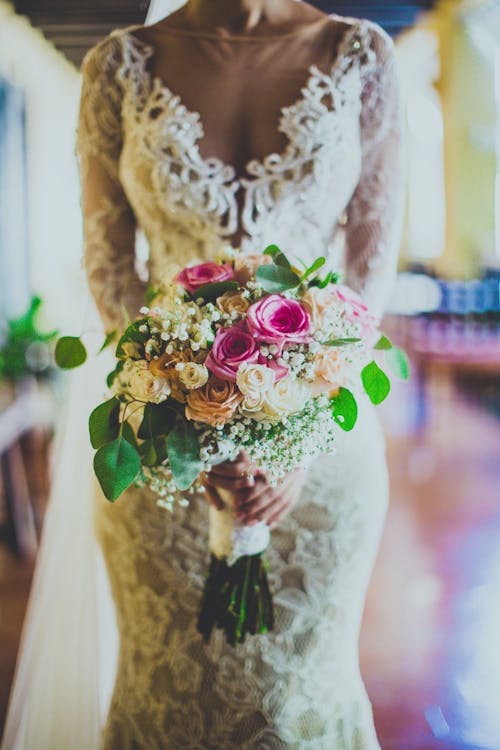 Crop elegant bride with roses bouquet