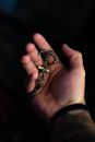 From above crop anonymous male showing anchor shaped breloque placed on palm in dark room