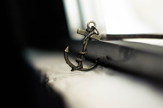 Selective focus of metal anchor styled keychain with thin leather strap abandoned on shabby windowsill