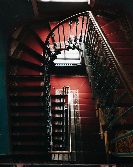 From above of aged stylish stairway with vintage railings and red carpet at daytime