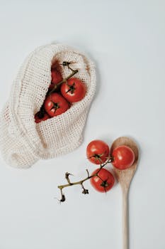 Cherry tomatoes in a reusable bag with a wooden spoon on a light background, illustrating eco-friendly food storage.