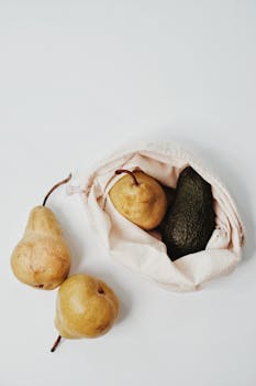 Pears and an avocado in a sustainable cotton bag, promoting eco-friendly shopping.