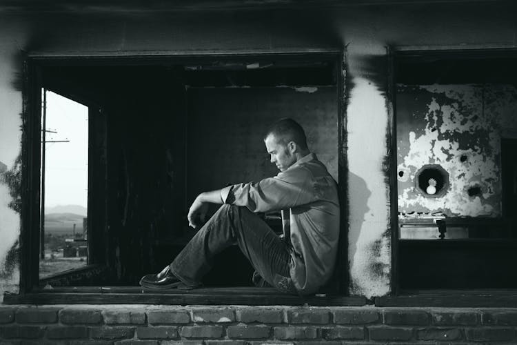 Grayscale Photo Of Man Sitting