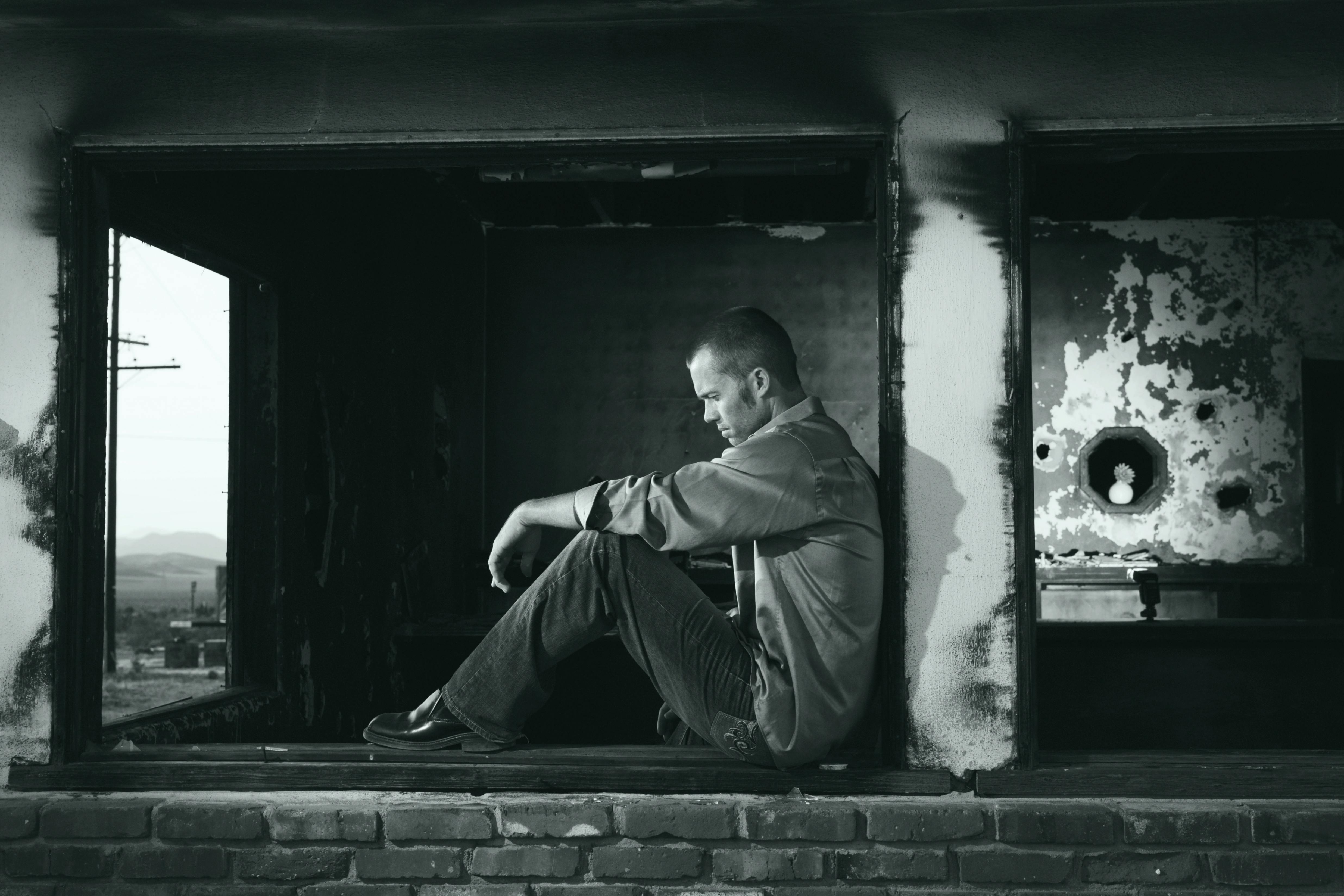 Grayscale Photo Of Man Sitting Free Stock Photo