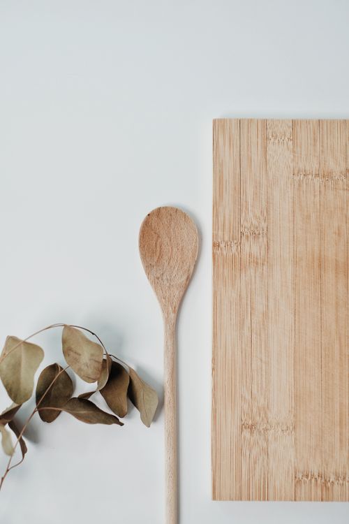 Free Flat lay of wooden spoon, chopping board, and eucalyptus leaves for eco-friendly kitchen decor. Stock Photo