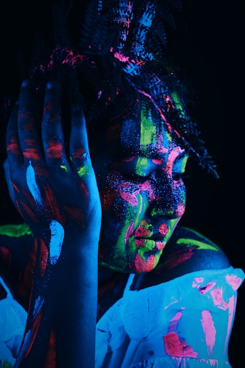 Creative woman with bright neon paints and shimmer on body