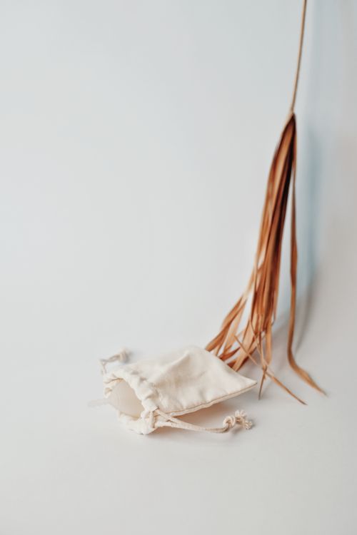 Free Simple white pouch against a soft backdrop with dry leaves, emphasizing eco-friendly and zero waste concepts. Stock Photo
